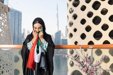 Union Day, December 2, Emirati Gulf Arab woman wearing hijab and abaya holding the UAE flag, Flag Day, November 3, love and pride of the homeland, gestures of happiness, pride and honor, remembering the UAE National Day 1971