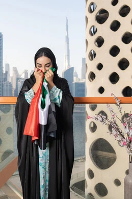 يوم العلم 3 نوفمبر، حب الوطن والاعتزاز به، ايماءات السعادة والفخر والاعتزاز، استذكار اليوم الوطني الاماراتي 1971، ذكرى تأسيس الاتحاد 2 ديسمبر، إمراة عربية خليجية إماراتية ترتدي الحجاب والعباءة تمسك بيدها علم الإمارات العربية المتحدة