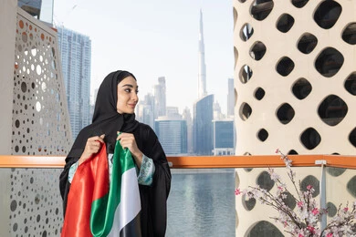UAE National Day 1971 Commemoration, the anniversary of the founding of the Union, December 2, an Emirati Gulf Arab woman wearing a hijab and abaya holding the UAE flag, Flag Day, November 3, love and pride of the homeland, gestures of happiness, pride and pride