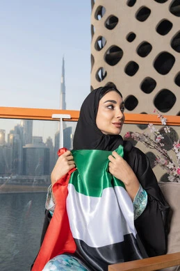 ذكرى تأسيس الاتحاد 2 ديسمبر، إمراة عربية خليجية إماراتية ترتدي الحجاب والعباءة تمسك بيدها علم الإمارات العربية المتحدة ، يوم العلم 3 نوفمبر، حب الوطن والاعتزاز به، ايماءات السعادة والفخر والاعتزاز، استذكار اليوم الوطني الاماراتي 1971