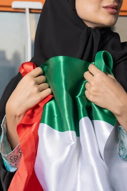 ذكرى تأسيس الاتحاد 2 ديسمبر، إمراة عربية خليجية إماراتية ترتدي الحجاب والعباءة تمسك بيدها علم الإمارات العربية المتحدة ، يوم العلم 3 نوفمبر، حب الوطن والاعتزاز به، ايماءات السعادة والفخر والاعتزاز، استذكار اليوم الوطني الاماراتي 1971
