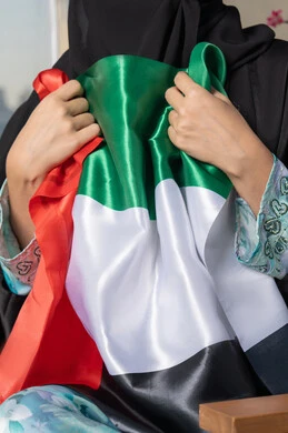 استذكار اليوم الوطني الاماراتي 1971، ذكرى تأسيس الاتحاد 2 ديسمبر، إمراة عربية خليجية إماراتية ترتدي الحجاب والعباءة تمسك بيدها علم الإمارات العربية المتحدة ، يوم العلم 3 نوفمبر، حب الوطن والاعتزاز به، ايماءات السعادة والفخر والاعتزاز