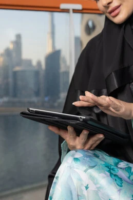 Gestures of concentration and integration, business management and completing required tasks, remote work, female profession and job, veiled Emirati Gulf Arab woman wearing an abaya using a laptop, using a modern and advanced technical device