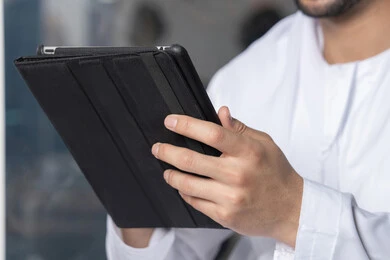 ايماءات السرور والسعادة، استخدام جهاز تقني حديث ومتطور، رجل عربي خليجي اماراتي يرتدي الكندورة والغترة البيضاء يستخدم الجهاز اللوحي، إنجاز مهام العمل عن بعد، إدارة شؤون الأعمال وتنظيمها عبر الايباد