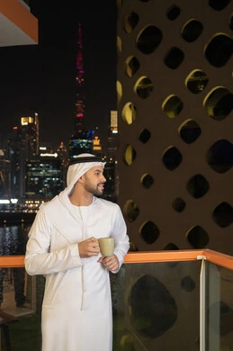الاستمتاع بالمشروبات الساخنة، رجل عربي خليجي اماراتي يرتدي الكندورة والغترة البيضاء  يقوم بشرب القهوة في المقهى، إيماءات السعادة والسرور، قضاء وقت الفراغ باحتساء المشروب المفضل، تناول الأعشاب الشتوية الدافئة