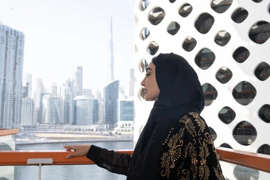 منظر جوي لناطحات السحاب, الهدوء والاستمتاع بالنظر من شرفة راقية, قضاء وقت ممتع في المقهى, شابة عربية خليجية اماراتية محجبة ترتدي عباءة سوداء مطرزة باللون الذهبي