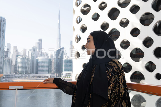لحظة صفاء راقية, الهدوء والاستمتاع بالنظر من شرفة راقية, قضاء وقت ممتع في المقهى, شابة عربية خليجية اماراتية محجبة ترتدي عباءة سوداء مطرزة باللون الذهبي