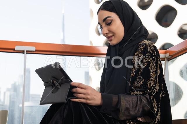احتراف الوظائف التقنية وتكنولوجيا المعلومات، متابعة آخر الأخبار على مواقع الانترنت، شابة عربية خليجية اماراتية محجبة ترتدي عباءة سوداء مطرزة باللون الذهبي