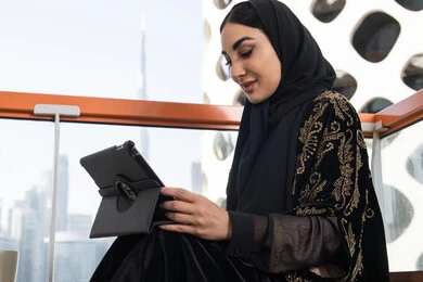 Professionalism in technical and information technology jobs, following the latest news on the Internet, a young veiled Emirati Gulf Arab woman wearing a black abaya embroidered with gold