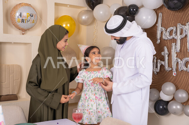 Decoration, hanging balloons and celebration, an Emirati Gulf Arab family celebrating their daughter's birthday, feelings of love and tenderness in a happy family gathering, gestures of happiness and joy, a joyful atmosphere for an Emirati family, happy holidays and occasions, strengthening family ties, feelings of love and tenderness in a happy family gathering, the concept of the importance of family