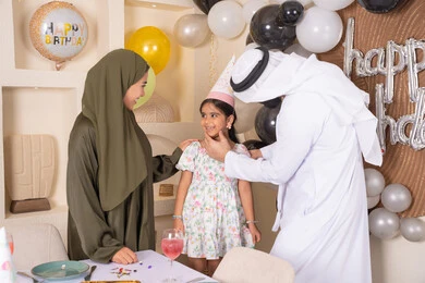 Strengthening family ties, feelings of love and tenderness in a happy family gathering, the concept of the importance of family, decoration, hanging balloons and celebration, gestures of happiness and pleasure, a joyful atmosphere for an Emirati family, happy holidays and occasions, an Arab Gulf Emirati family celebrating their daughter's birthday, feelings of love and tenderness in a happy family gathering
