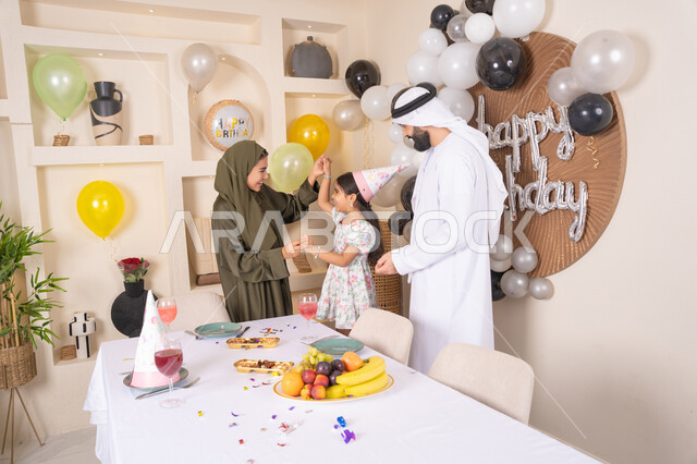 التزيين وتعليق البلالين والاحتفال، مفهوم الحب والالفه والموده، أجواء فرحة لأسرة اماراتية، ايماءات السعاده والسرور، مشاعر الحب والحنان في اجتماع عائلي سعيد، اعياد ومناسبات سعيدة،عائله عربيه خليجيه اماراتية تحتفل بعيد ميلاد ابنتهم
