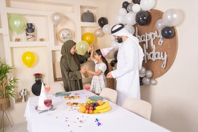 التزيين وتعليق البلالين والاحتفال، مفهوم الحب والالفه والموده، أجواء فرحة لأسرة اماراتية، ايماءات السعاده والسرور، مشاعر الحب والحنان في اجتماع عائلي سعيد، اعياد ومناسبات سعيدة،عائله عربيه خليجيه اماراتية تحتفل بعيد ميلاد ابنتهم