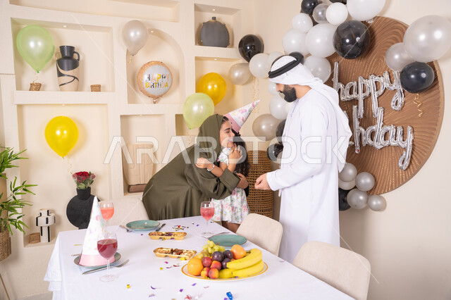 مفهوم الحب والالفه والموده، أجواء فرحة لأسرة اماراتية، ايماءات السعاده والسرور، مشاعر الحب والحنان في اجتماع عائلي سعيد، اعياد ومناسبات سعيدة،عائله عربيه خليجيه اماراتية تحتفل بعيد ميلاد ابنتهم ، تعليق الزينة والبالونات الملونة  ، ام اماراتيه تعانق ابنتها