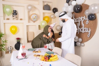 مفهوم الحب والالفه والموده، أجواء فرحة لأسرة اماراتية، ايماءات السعاده والسرور، مشاعر الحب والحنان في اجتماع عائلي سعيد، اعياد ومناسبات سعيدة،عائله عربيه خليجيه اماراتية تحتفل بعيد ميلاد ابنتهم ، تعليق الزينة والبالونات الملونة  ، ام اماراتيه تعانق ابنتها