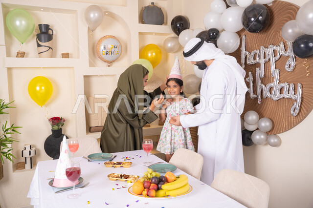 ايماءات السعاده والسرور، مشاركة لأجواء رائعة عائلية داخل المنزل، مشاعر الحب والحنان في اجتماع عائلي سعيد، اعياد ومناسبات سعيدة، مفهوم الحب والالفه والموده، عائله عربيه خليجيه اماراتية تحتفل بعيد ميلاد ابنتهم ، تعليق الزينة والبالونات الملونة