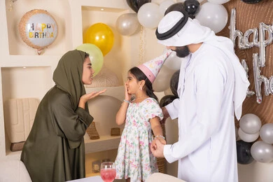 مشاركة لأجواء رائعة عائلية داخل المنزل، مشاعر الحب والحنان في اجتماع عائلي سعيد، اعياد ومناسبات سعيدة، مفهوم الحب والالفه والموده، عائله عربيه خليجيه اماراتية تحتفل بعيد ميلاد ابنتهم ، ام اماراتيه تقوم بتقبيل ابنتها ،  تعليق الزينة والبالونات الملونة ، ايماءات السعاده والسرور