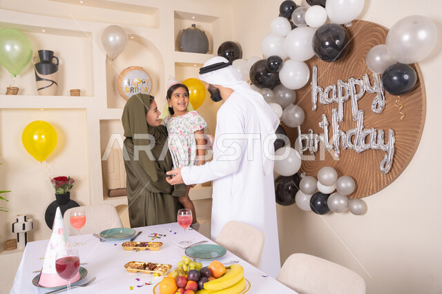 ام اماراتيه تحمل ابنتها لاعلى بتعابير البهجة، مشاركة لأجواء رائعة عائلية داخل المنزل، تعليق الزينة والبالونات الملونة ، ايماءات السعاده والسرور ، اعياد ومناسبات سعيدة،  مشاعر الحب والحنان في اجتماع عائلي سعيد، مفهوم الحب والالفه والموده، عائله عربيه خليجيه اماراتية تحتفل بعيد ميلاد ابنتهم