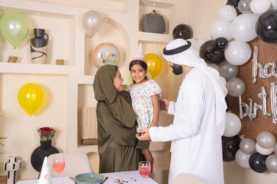 مشاركة لأجواء رائعة عائلية داخل المنزل، تعليق الزينة والبالونات الملونة ، ايماءات السعاده والسرور ، اعياد ومناسبات سعيدة،  مشاعر الحب والحنان في اجتماع عائلي سعيد، مفهوم الحب والالفه والموده، عائله عربيه خليجيه اماراتية تحتفل بعيد ميلاد ابنتهم ، ام اماراتيه تحمل ابنتها لاعلى بتعابير البهجة