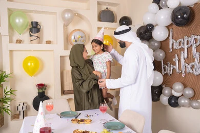 تعليق الزينة والبالونات الملونة ،  مشاركة لأجواء رائعة عائلية داخل المنزل، ايماءات السعاده والسرور ، اعياد ومناسبات سعيدة،  مشاعر الحب والحنان في اجتماع عائلي سعيد، مفهوم الحب والالفه والموده، عائله عربيه خليجيه اماراتية تحتفل بعيد ميلاد ابنتهم