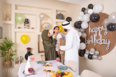 ايماءات السعاده والسرور ، اعياد ومناسبات سعيدة،  مشاعر الحب والحنان في اجتماع عائلي سعيد، مفهوم الحب والالفه والموده، تعليق الزينة والبالونات الملونة ،  مشاركة لأجواء رائعة عائلية داخل المنزل، عائله عربيه خليجيه اماراتية تحتفل بعيد ميلاد ابنتهم