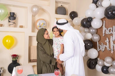 مشاعر الحب والحنان في اجتماع عائلي سعيد، مفهوم الحب والالفه والموده، ايماءات السعاده والسرور ، اعياد ومناسبات سعيدة،  تعليق الزينة والبالونات الملونة ،  مشاركة لأجواء رائعة عائلية داخل المنزل، عائله عربيه خليجيه اماراتية تحتفل بعيد ميلاد ابنتهم وتقبيلها