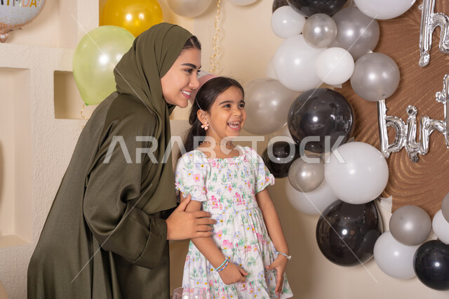 مفهوم الحب والالفه والموده، ايماءات السعاده والسرور ، اعياد ومناسبات سعيدة،  تعليق الزينة والبالونات الملونة ،  مشاركة لأجواء رائعة عائلية داخل المنزل، عائله عربيه خليجيه اماراتية تحتفل بعيد ميلاد ابنتهم