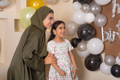 مفهوم الحب والالفه والموده، ايماءات السعاده والسرور ، اعياد ومناسبات سعيدة،  تعليق الزينة والبالونات الملونة ،  مشاركة لأجواء رائعة عائلية داخل المنزل، عائله عربيه خليجيه اماراتية تحتفل بعيد ميلاد ابنتهم