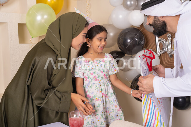 مشاركة لأجواء رائعة عائلية داخل المنزل، ايماءات السعاده والسرور ، رجل اماراتي يقوم بتقديم الهديه ويفاجئ ابنته ،تعليق الزينة والبالونات الملونة ، اعياد ومناسبات سعيدة، مفهوم الحب والالفه والموده، عائله عربيه خليجيه اماراتية تحتفل بعيد ميلاد ابنتهم
