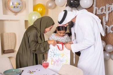 اعياد ومناسبات سعيدة، مفهوم الحب والالفه والموده، تعابير المفاجأه والسعادة و السرور، عائله عربيه خليجيه اماراتية تحتفل بعيد ميلاد ابنتهم وتقدم الهدايا ،تقديم الهدايا والمفاجآت للأطفال، مشاركة لأجواء رائعة عائلية داخل المنزل، تعليق الزينة والبالونات الملونة