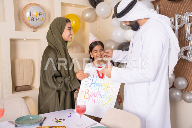 مشاركة لأجواء رائعة عائلية داخل المنزل، تعليق الزينة والبالونات الملونة، تعابير المفاجأه والسعادة و السرور، عائله عربيه خليجيه اماراتية تحتفل بعيد ميلاد ابنتهم وتقدم الهدايا ،اعياد ومناسبات سعيدة، تقديم الهدايا والمفاجآت للأطفال، مفهوم الحب والالفه والموده
