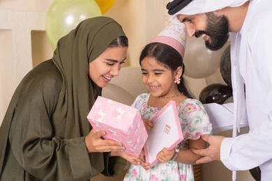 مفهوم الحب والالفه والموده، تقديم الهدايا والمفاجآت للأطفال، مشاركة لأجواء رائعة عائلية داخل المنزل،  ايماءات السعادة و السرور، عائله عربيه خليجيه اماراتية تحتفل بعيد ميلاد ابنتهم ،اعياد ومناسبات سعيدة، تعليق الزينة والبالونات الملونة، ام اماراتيه تقوم بتقديم الهديه لابنتها