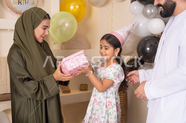 مشاركة لأجواء رائعة عائلية داخل المنزل،  ايماءات السعادة و السرور، عائله عربيه خليجيه اماراتية تحتفل بعيد ميلاد ابنتهم ،اعياد ومناسبات سعيدة، تعليق الزينة والبالونات الملونة، ام اماراتيه تقوم بتقديم الهديه لابنتها ،مفهوم الحب والالفه والموده، تقديم الهدايا والمفاجآت للأطفال