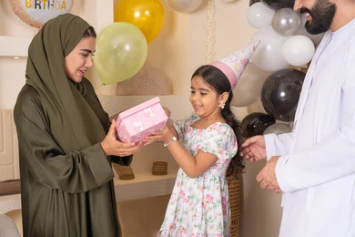 مشاركة لأجواء رائعة عائلية داخل المنزل،  ايماءات السعادة و السرور، عائله عربيه خليجيه اماراتية تحتفل بعيد ميلاد ابنتهم ،اعياد ومناسبات سعيدة، تعليق الزينة والبالونات الملونة، ام اماراتيه تقوم بتقديم الهديه لابنتها ،مفهوم الحب والالفه والموده، تقديم الهدايا والمفاجآت للأطفال