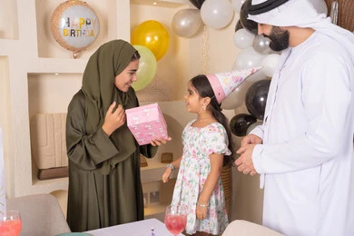 ايماءات السعادة و السرور، مشاركة لأجواء رائعة عائلية داخل المنزل، عائله عربيه خليجيه اماراتية تحتفل بعيد ميلاد ابنتهم ،اعياد ومناسبات سعيدة، تعليق الزينة والبالونات الملونة، ام اماراتيه تقوم بتقديم الهديه لابنتها ،مفهوم الحب والالفه والموده، تقديم الهدايا والمفاجآت للأطفال