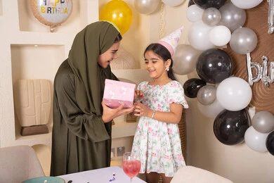 ايماءات السعادة و السرور، مشاركة لأجواء رائعة عائلية داخل المنزل،عائله عربيه خليجيه اماراتية تحتفل بعيد ميلاد ابنتهم ، تعليق الزينة والبالونات الملونة، ام اماراتيه تقوم بتقديم الهديه لابنتها ،مفهوم الحب والالفه والموده، تقديم الهدايا والمفاجآت للأطفال، اعياد ومناسبات سعيدة