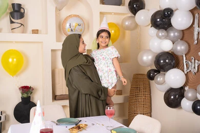 ايماءات السعادة و السرور، تقديم الهدايا والمفاجآت للأطفال، تعليق الزينة والبالونات الملونة، اعياد ومناسبات سعيدة، ام عربية خليجية تحمل ابنتها  للاعلى ، عائله عربيه خليجيه اماراتية تقوم بالاحتفال بعيد ميلاد ابنتهم