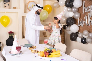 عائله عربيه خليجيه اماراتية تقوم بالاحتفال بعيد ميلاد ابنتهم ، تقديم الهدايا والمفاجآت للأطفال، تعليق الزينة والبالونات الملونة، اب عربي خليجي يحتفل بابنته بايماءات السعادة و السرور، اعياد ومناسبات سعيدة