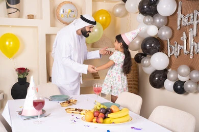 تقديم الهدايا والمفاجآت للأطفال، تعليق الزينة والبالونات الملونة، اب عربي خليجي يحتفل بابنته بايماءات السعادة و السرور، اعياد ومناسبات سعيدة، عائله عربيه خليجيه اماراتية تقوم بالاحتفال بعيد ميلاد ابنتهم