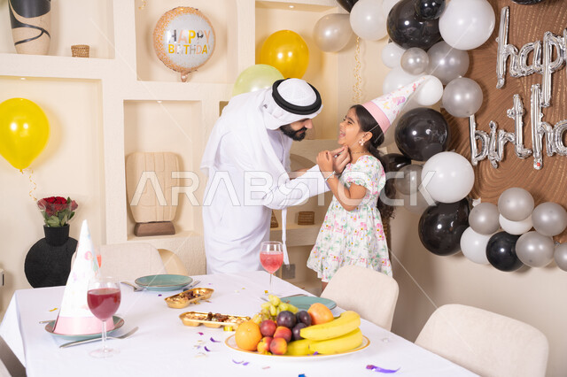 اب عربي خليجي يحتفل بابنته بايماءات السعادة و السرور، اعياد ومناسبات سعيدة، عائله عربيه خليجيه اماراتية تقوم بالاحتفال بعيد ميلاد ابنتهم ، تقديم الهدايا والمفاجآت للأطفال، تعليق الزينة والبالونات الملونة