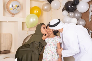 اجتماع عائلي سعيد، تعزيز الروابط العائلية والمحبة والمودة بين الأسره ، مناسبات وأعياد سعيدة ، عائلة عربية خليجية إماراتية تقوم بالاحتفال وتقبيل ابنتهم ، إيماءات الحب والحنان والاهتمام بالابناء