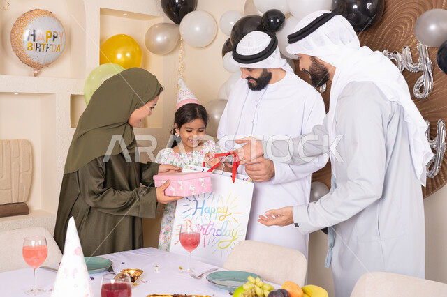 ام اماراتيه تقوم بتقديم الهديه لابنتها، إيماءات الفرح و السعادة، تعزيز الروابط العائلية والمحبة والمودة بين الأسرة،  مناسبات وأعياد سعيدة، عائلة عربية خليجية إماراتية تقوم بالاحتفال ،مشاعر الحب والحنان في اجتماع عائلي سعيد