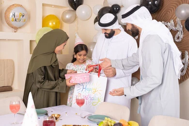 ام اماراتيه تقوم بتقديم الهديه لابنتها، إيماءات الفرح و السعادة، تعزيز الروابط العائلية والمحبة والمودة بين الأسرة،  مناسبات وأعياد سعيدة، عائلة عربية خليجية إماراتية تقوم بالاحتفال ،مشاعر الحب والحنان في اجتماع عائلي سعيد