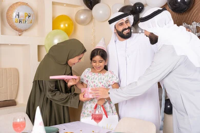 Gestures of joy and happiness, strengthening family ties, love and affection between the family, happy occasions and holidays, an Emirati Gulf Arab family celebrating, an Emirati mother presenting a gift to her daughter, feelings of love and tenderness in a happy family gathering
