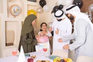 Happy occasions and holidays, strengthening family ties, love and affection between the family, an Emirati Gulf Arab family celebrating, an Emirati mother presenting a gift to her daughter, gestures of joy and happiness, feelings of love and tenderness in a happy family gathering