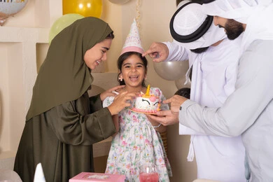أجواء أسرية مليئة بالألفة،مشاركة وتقديم الهدايا بالمناسبات وأعياد الميلاد، مشاعر الحب والحنان في اجتماع عائلي سعيد، إيماءات الفرح و السعادة، عائلة عربية خليجية إماراتية تحتفل بعيد ميلاد ابنتهم ، بلالين وكعكة يوم الميلاد المزينة بالشموع