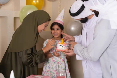 مشاعر الحب والحنان في اجتماع عائلي سعيد، إيماءات الفرح و السعادة، بلالين وكعكة يوم الميلاد المزينة بالشموع، أجواء أسرية مليئة بالألفة،مشاركة وتقديم الهدايا بالمناسبات وأعياد الميلاد،عائلة عربية خليجية إماراتية تحتفل بعيد ميلاد ابنتهم