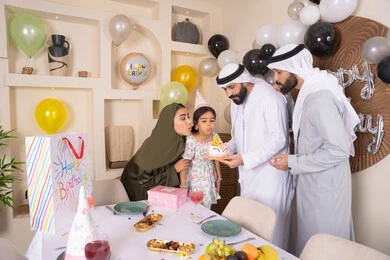 مشاعر الحب والحنان في اجتماع عائلي سعيد، مشاركة وتقديم الهدايا بالمناسبات وأعياد الميلاد، أجواء أسرية مليئة بالألفة، بلالين وكعكة يوم الميلاد المزينة بالشموع، عائلة عربية خليجية إماراتية تقضي أوقات ممتعه في المنزل ، إيماءات الفرح و السعادة
