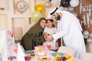 مشاعر الحب والحنان في اجتماع عائلي سعيد, أجواء أسرية مليئة بالألفة، بلالين وكعكة يوم الميلاد المزينة بالشموع، عائلة عربية خليجية إماراتية تقضي أوقات ممتعه في المنزل، إيماءات الفرح و السعادة، مشاركة وتقديم الهدايا بالمناسبات وأعياد الميلاد