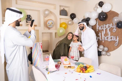 قضاء أوقات ممتعه و الاحتفال بالمناسبات العائلية، توثيق اللحظات السعيدة، زينة أعياد الميلاد و المناسبات، عائله عربيه خليجيه اماراتية تقوم بالاحتفال بعيد الميلاد ، رجل يقوم بالتقاط صورة تذكارية من خلال الجوال ، ايماءات السعادة و السرور